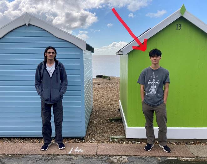 Two men standing in front of a green and blue building

Description automatically generated