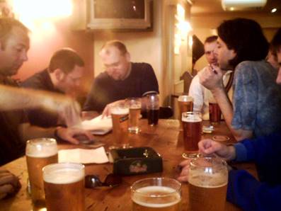 A group of people sitting around a table with glasses of beer

Description automatically generated with medium confidence