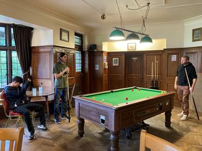 A group of people playing pool

Description automatically generated