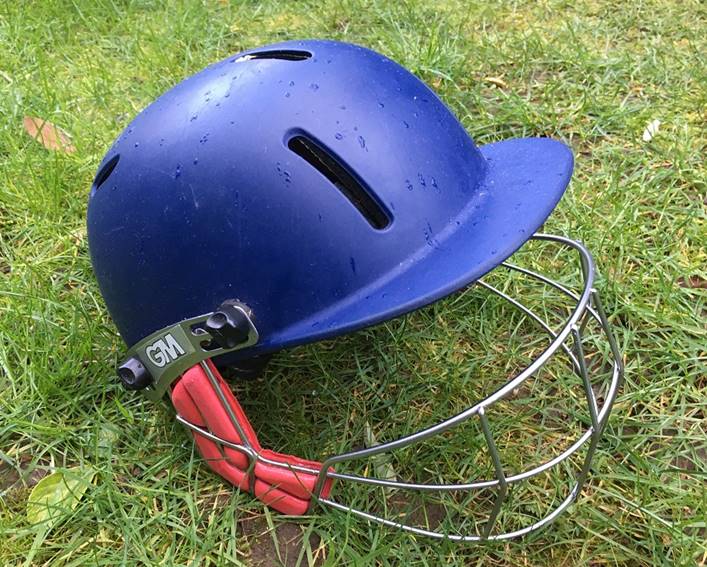 A close up of a helmet lying on the grass

Description automatically generated